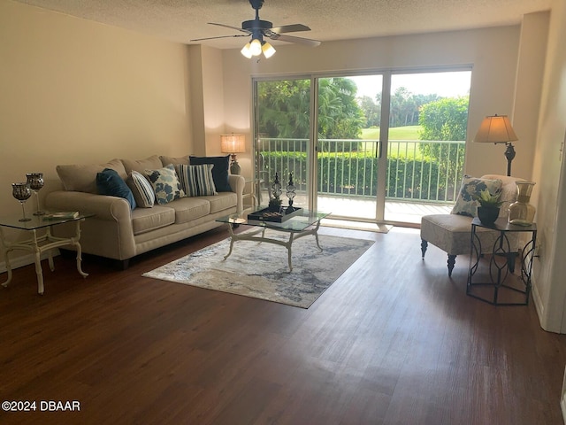 living room with a textured ceiling, ceiling fan, and dark wood-type flooring