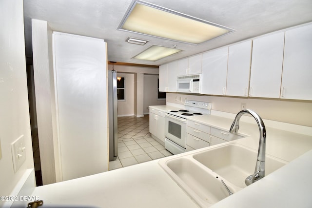 kitchen featuring sink, white cabinets, light tile patterned flooring, and white appliances