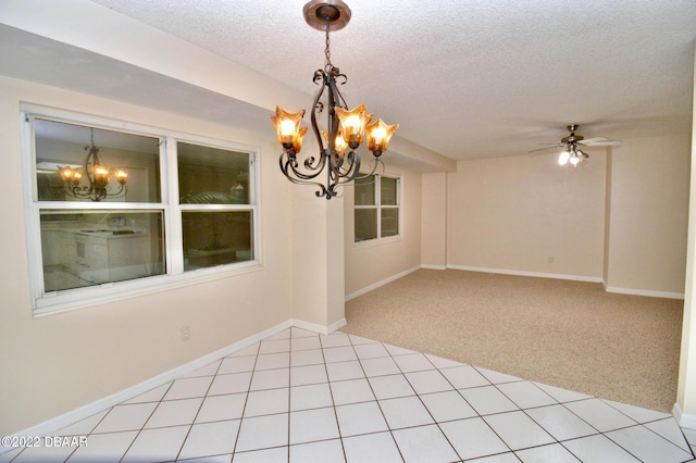 carpeted spare room with a textured ceiling and ceiling fan with notable chandelier