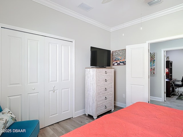 bedroom with crown molding, wood finished floors, visible vents, and a closet