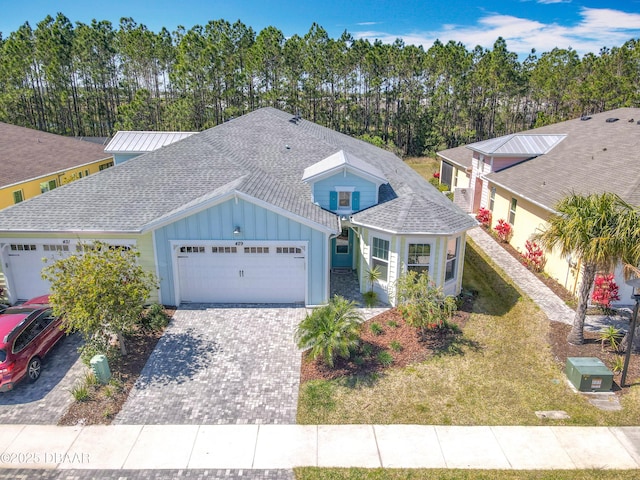 view of front of home with board and batten siding, a shingled roof, a front yard, driveway, and an attached garage