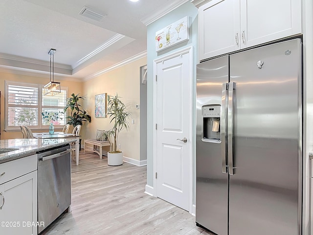 kitchen featuring visible vents, a tray ceiling, appliances with stainless steel finishes, crown molding, and light wood-type flooring