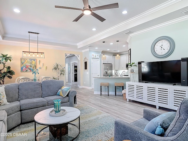 living room featuring visible vents, crown molding, ceiling fan, light wood-type flooring, and arched walkways