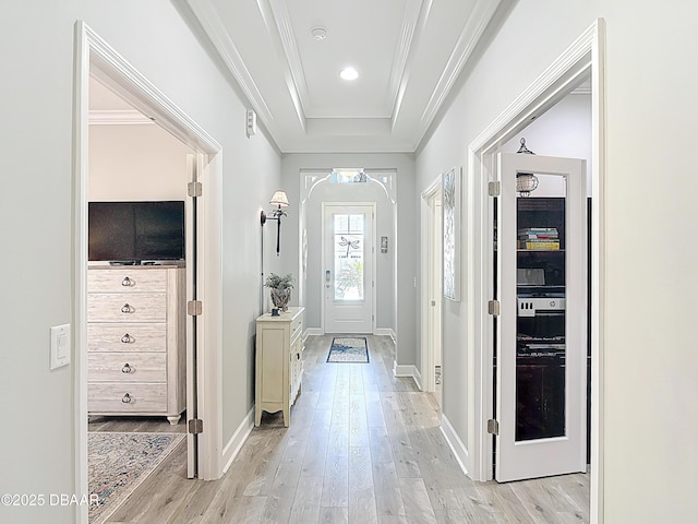 foyer with ornamental molding, a tray ceiling, recessed lighting, light wood finished floors, and baseboards