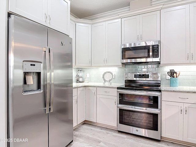 kitchen with backsplash, stainless steel appliances, light stone counters, and light wood-style floors