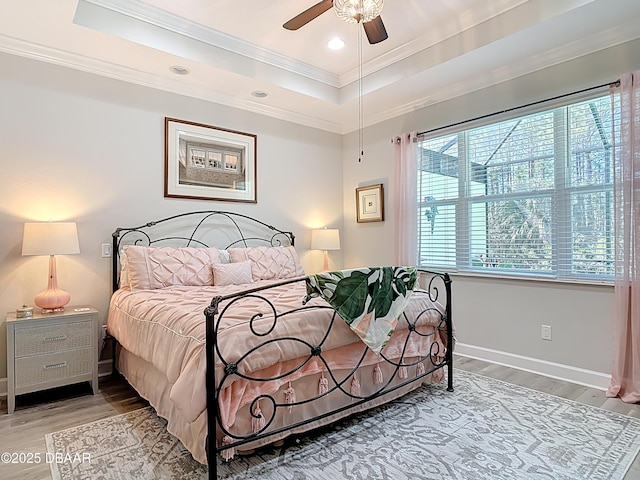 bedroom featuring a raised ceiling, wood finished floors, and crown molding