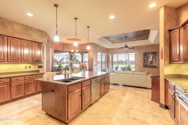 kitchen featuring stainless steel appliances, a tray ceiling, ceiling fan, sink, and pendant lighting