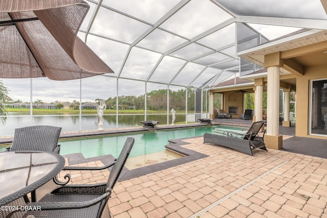 view of pool with glass enclosure, a water view, and a patio