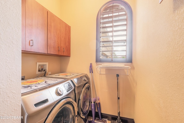 clothes washing area with washer and dryer and cabinets