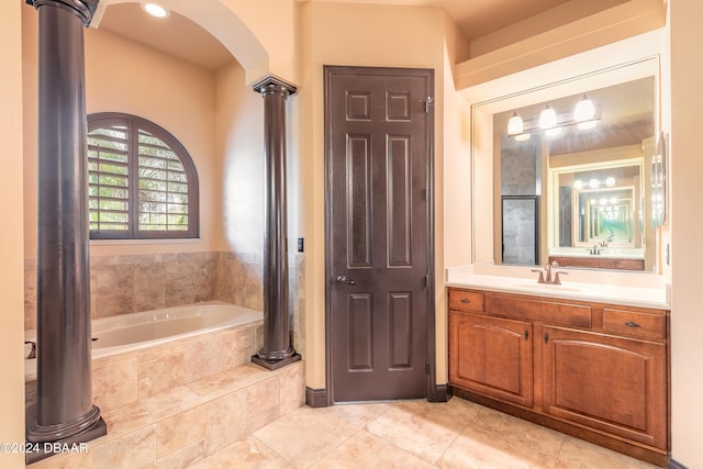 bathroom with tile patterned flooring, vanity, and tiled bath