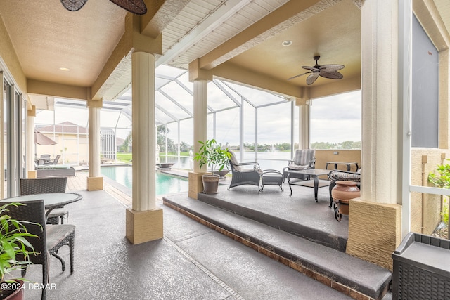 sunroom featuring beam ceiling, ceiling fan, and a swimming pool