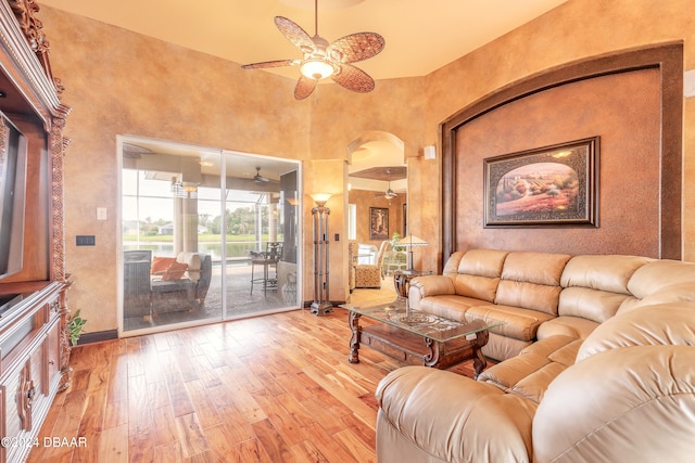 living room with ceiling fan, wood-type flooring, and a high ceiling