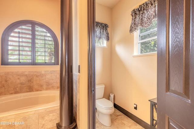 bathroom featuring tile patterned flooring, a relaxing tiled tub, toilet, and plenty of natural light