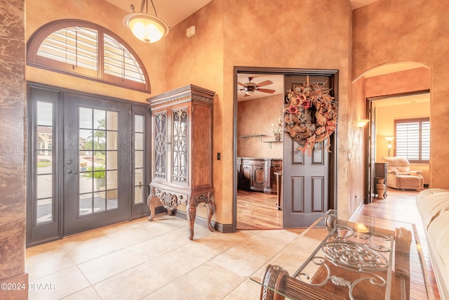 entryway featuring ceiling fan, a towering ceiling, and light tile patterned floors