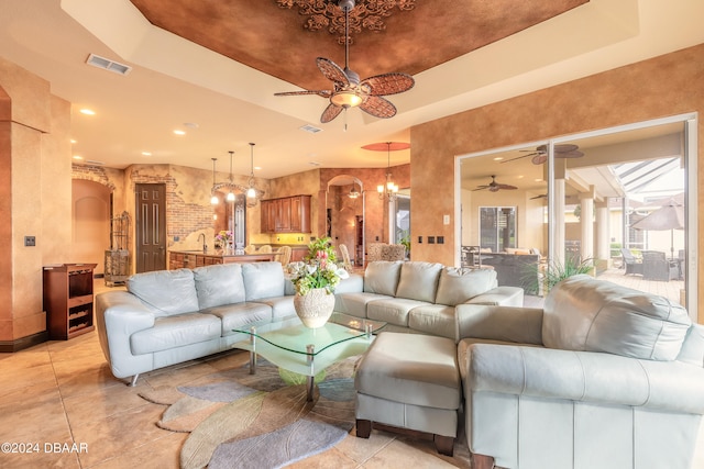 living room with a chandelier, light tile patterned flooring, a raised ceiling, and sink