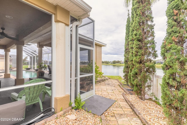 view of patio featuring a water view, glass enclosure, and ceiling fan