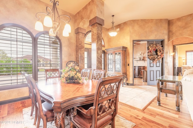 dining room with high vaulted ceiling, a notable chandelier, and light wood-type flooring