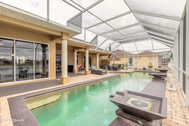 view of swimming pool featuring glass enclosure, ceiling fan, outdoor lounge area, and a patio