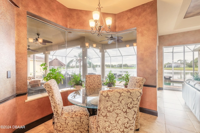 tiled dining room with ceiling fan with notable chandelier and a water view