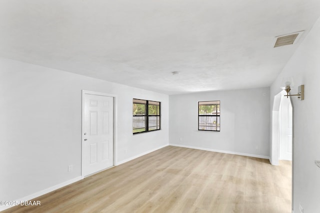 empty room with visible vents, baseboards, and light wood-type flooring