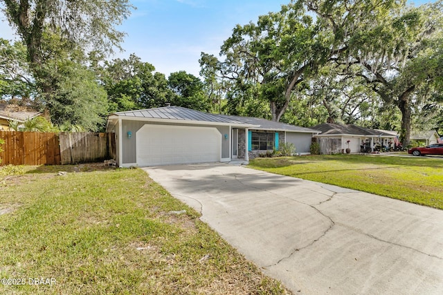 ranch-style home featuring metal roof, a front yard, fence, concrete driveway, and an attached garage