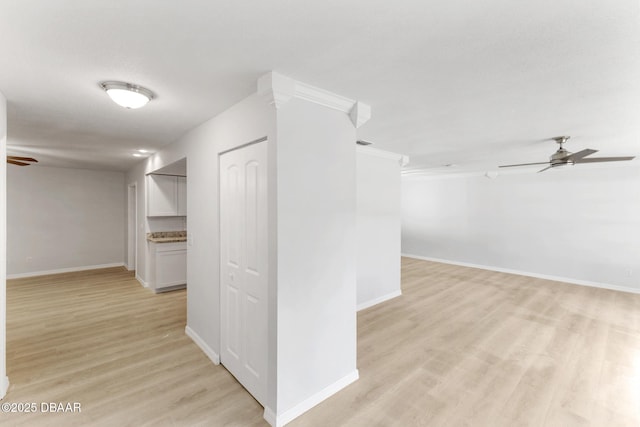 hallway featuring baseboards, ornamental molding, and light wood finished floors