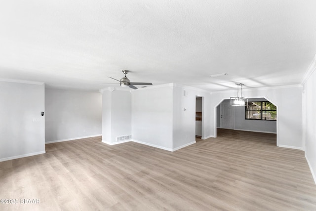unfurnished living room featuring crown molding, ceiling fan, light wood-style floors, baseboards, and visible vents
