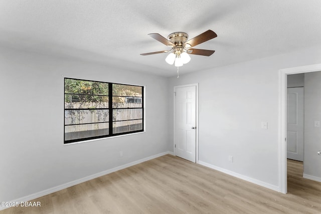 spare room featuring a textured ceiling, ceiling fan, baseboards, and light wood finished floors