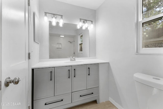 bathroom with vanity, baseboards, walk in shower, and toilet