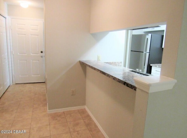 kitchen with light tile patterned flooring and stainless steel fridge