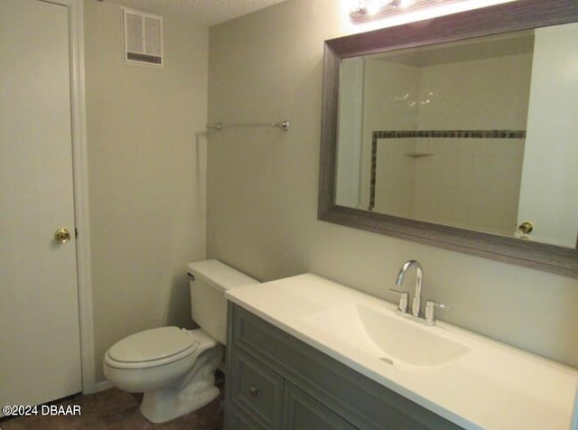 bathroom with vanity, a textured ceiling, toilet, and a shower