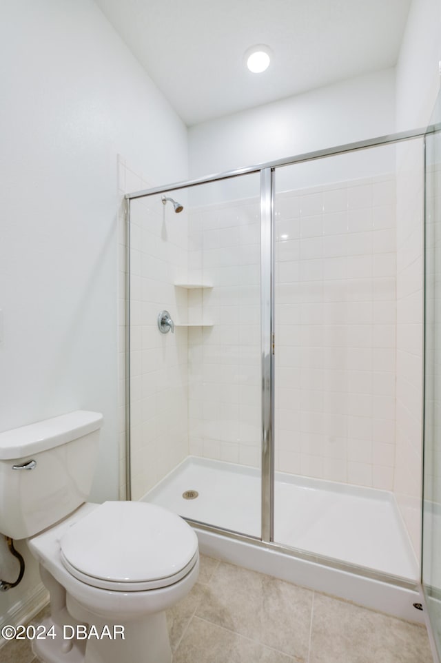 bathroom featuring a shower with shower door, tile patterned flooring, and toilet