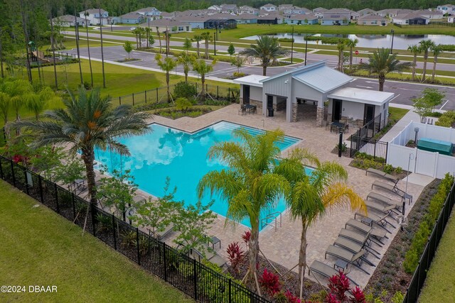 view of pool featuring a yard, a water view, and a patio area