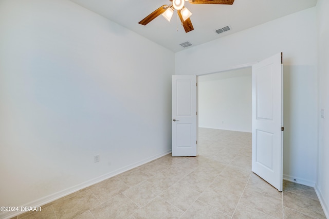 empty room with ceiling fan and light tile patterned flooring