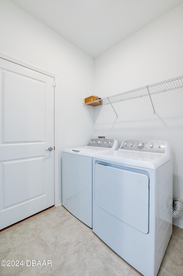 clothes washing area featuring separate washer and dryer and light tile patterned floors