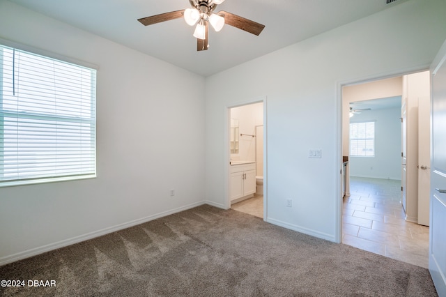 unfurnished bedroom featuring light colored carpet, ceiling fan, and ensuite bathroom