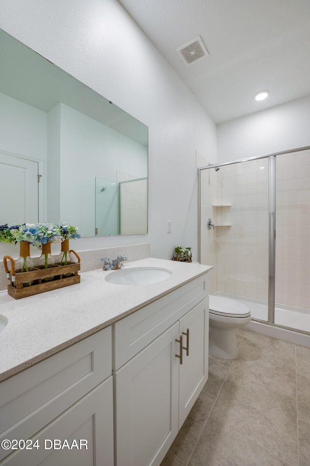 bathroom with tile patterned flooring, vanity, toilet, and a shower with door