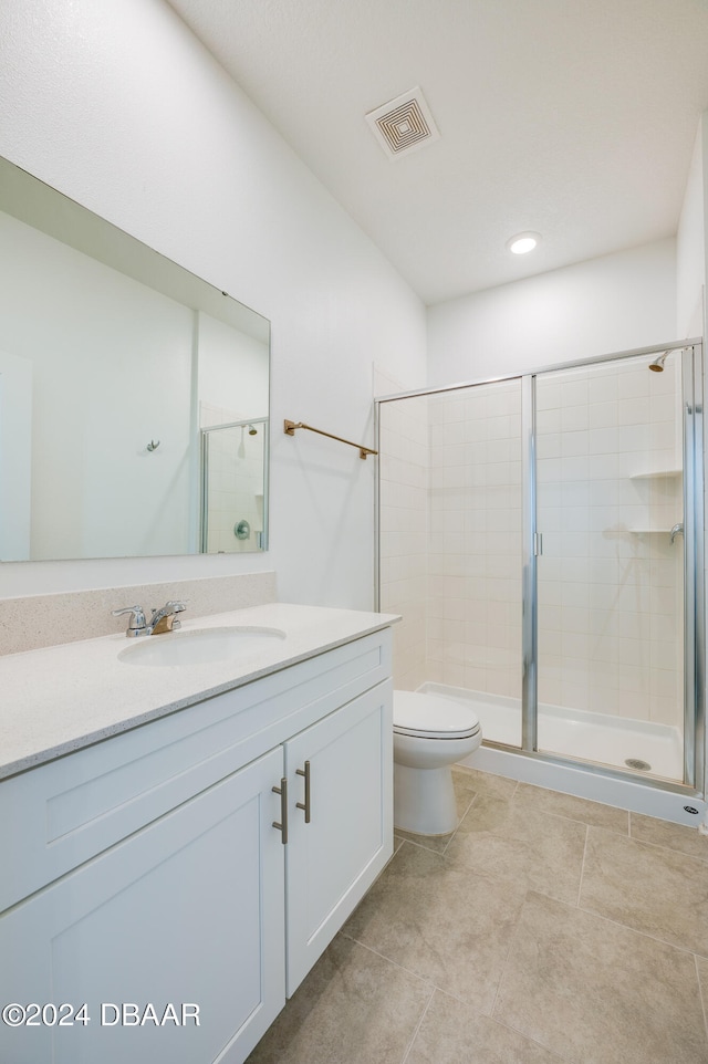 bathroom with toilet, vanity, tile patterned floors, and a shower with shower door