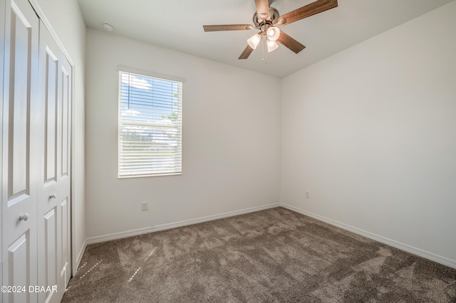 unfurnished room with dark colored carpet and ceiling fan