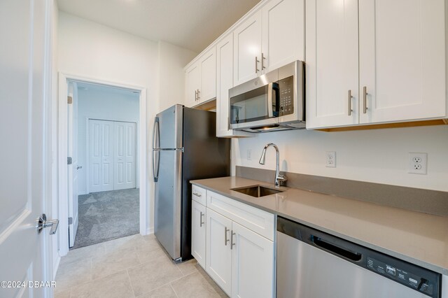 kitchen with white cabinets, stainless steel appliances, sink, and light tile patterned floors