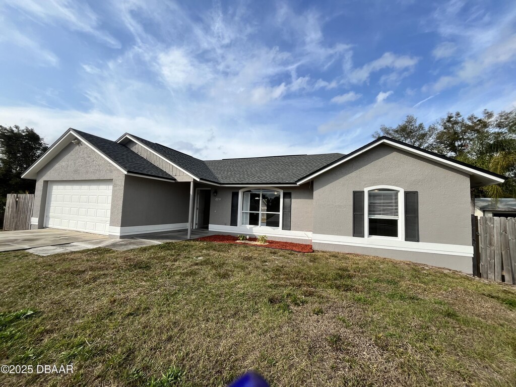 ranch-style home with a garage and a front lawn