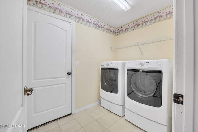 laundry area with washer and clothes dryer, light tile patterned floors, and a textured ceiling