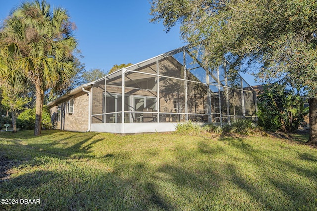 back of house with a yard and a lanai