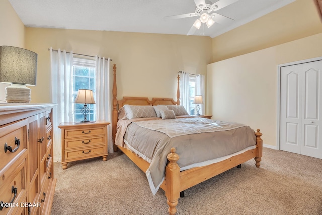 bedroom featuring ceiling fan, a closet, light colored carpet, and lofted ceiling