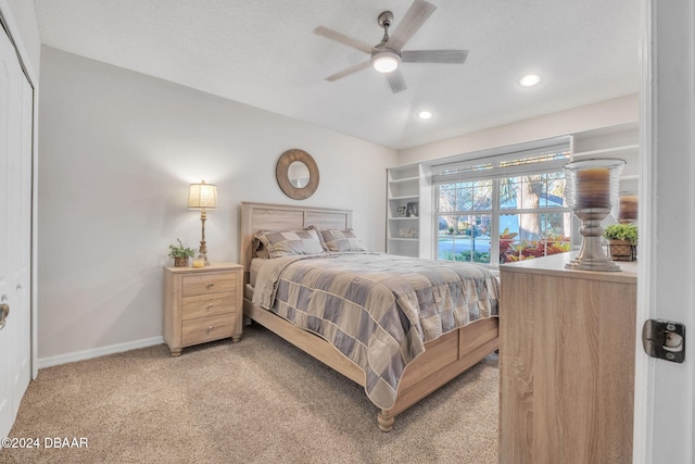 bedroom with ceiling fan, a closet, light colored carpet, and a textured ceiling