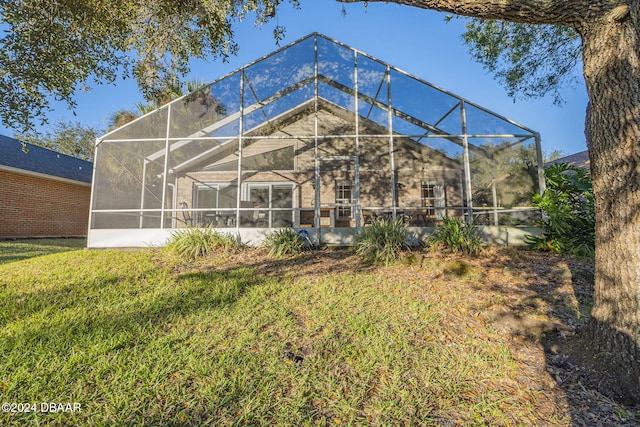 rear view of house with a yard and a lanai