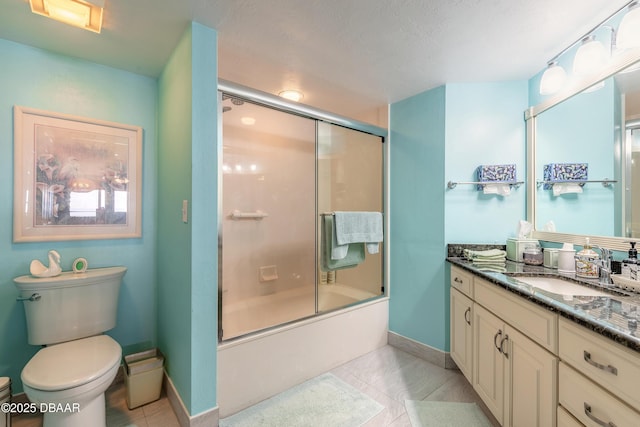 bathroom featuring toilet, bath / shower combo with glass door, vanity, baseboards, and tile patterned floors