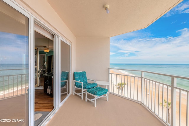 balcony with a view of the beach, a sunroom, and a water view