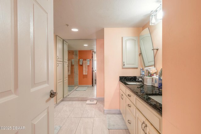 bathroom with double vanity, baseboards, a shower stall, a sink, and recessed lighting