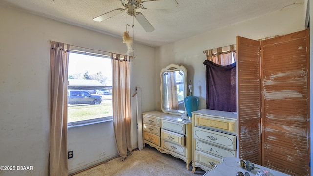 carpeted bedroom featuring ceiling fan and a textured ceiling